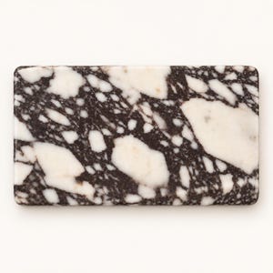 May include: A rectangular slab featuring a high-contrast pattern of irregular, angular white shapes interspersed with dark brown, almost black, veining. The surface has a smooth, polished appearance with rounded corners and a consistent, dense texture.