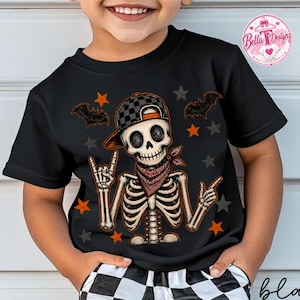 May include: A black t-shirt featuring a graphic of a skeleton wearing a black and gray checkered baseball cap and a red patterned bandana. The skeleton is making a rock-and-roll hand gesture, surrounded by orange and gray stars and black bats.