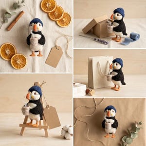 May include: A needle-felted puffin figurine wearing a dark blue knit hat and holding a small beige mug. The puffin has a black and white body with an orange beak. It is shown in various settings with dried orange slices, gift boxes, and a wooden easel.