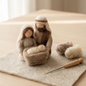 Könnte beinhalten: Eine Krippenszene aus Nadelfilz mit drei Figuren in Beige- und Brauntönen. Das Set enthält zwei erwachsene Figuren, ein kleines Kind in einer Krippe sowie lose Wollvlies-Reste und ein Filznadelwerkzeug mit einem Holzgriff.