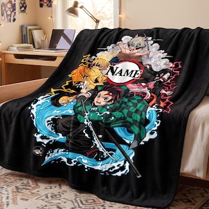 May include: A black fleece blanket featuring a graphic print of four anime characters in action poses with water, lightning, and smoke effects. The center includes a circular white emblem with the black text NAME printed inside.