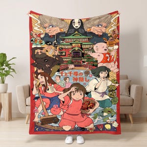 May include: A rectangular throw blanket featuring a vibrant, multi-colored graphic illustration of characters and the bathhouse from the film Spirited Away, with the Japanese text 千と千尋の神隠し printed in the center of the design.