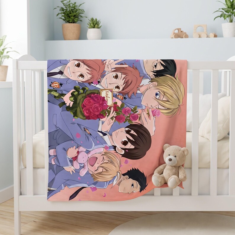 May include: A soft fleece blanket featuring a colorful anime-style illustration of seven characters in blue school uniforms. The group is gathered together with a bouquet of red roses and a small pink plush toy against a solid peach background.