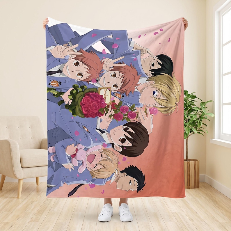 May include: A soft fleece blanket featuring a colorful anime-style illustration of seven characters in blue school uniforms. The group is surrounded by pink flower petals, with one character holding a bouquet of red roses and another a pink plush toy.