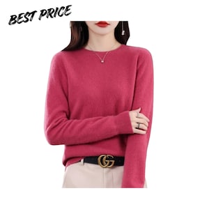 May include: A long-sleeved, crew-neck sweater in a vibrant magenta color with a soft, fuzzy texture. The sweater is worn tucked into light-colored trousers with a black belt featuring a gold-toned G-shaped buckle. The text BEST PRICE is visible.