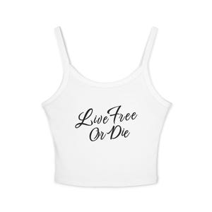Op de afbeelding: Een witte mouwloze crop top met dunne schouderbandjes en een ronde halslijn. De voorkant van het kledingstuk is voorzien van de zwarte cursieve tekst "Live Free Or Die" die in het midden op de borst is gedrukt voor een contrastrijk ontwerp.