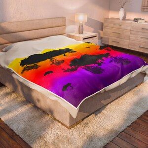 May include: A rectangular throw blanket featuring a vibrant gradient print that transitions from yellow to orange, red, and purple. The design includes black silhouettes of trees and foliage scattered across the colorful, sunset-inspired background.