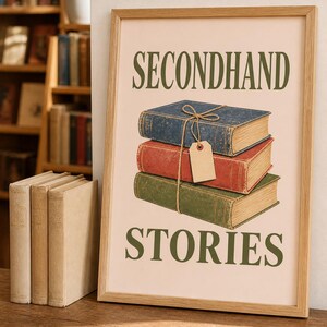 Peut inclure: Une affiche encadrée avec le texte SECONDHAND STORIES en lettres vert foncé. L'illustration centrale montre une pile de trois livres bleu, rouge et vert, attachés avec de la ficelle et une étiquette rectangulaire beige vierge.