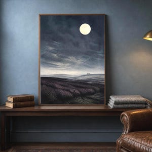 Op de afbeelding: Een ingelijste wandkunstprint met een donker, sfeervol nachtlandschap onder een volle maan. De scène toont glooiende heuvels, een getextureerd veld op de voorgrond en een bewolkte, diepblauwe lucht. Het kunstwerk zit in een dunne houten lijst.