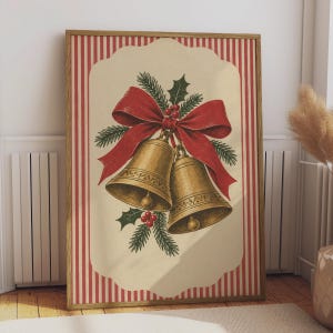 Può includere: Una stampa artistica da parete rettangolare incorniciata che presenta un'illustrazione in stile vintage di due campane dorate legate con un grande nastro rosso, accentuate da aghi di pino verdi e bacche rosse su sfondo crema con bordi a righe verticali rosse.
