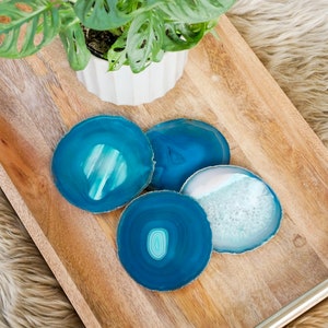 May include: Four blue agate coasters on a wooden tray. The coasters are round and have a natural, organic look.