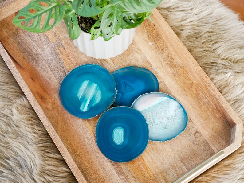 May include: Four blue agate coasters on a wooden tray. The coasters are round and have a natural, organic look.