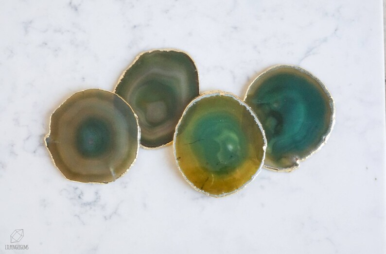 May include: Four agate coasters with gold trim. The coasters are green, yellow, and brown with a swirling pattern.