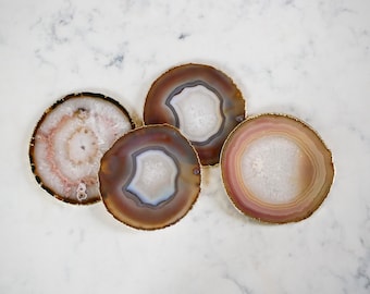 May include: Four agate coasters with gold trim. The coasters are round and have a natural, organic look. They are perfect for protecting surfaces from scratches and spills.