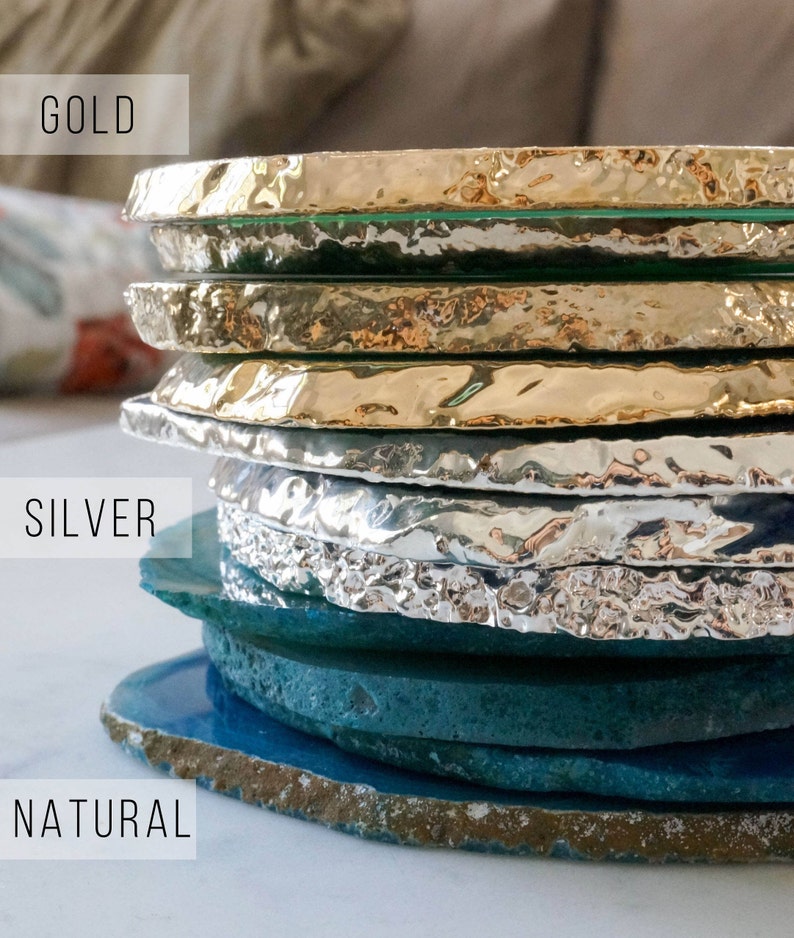 May include: Stack of agate coasters in natural, silver, and gold finishes. The coasters are round and have a rough, natural edge.