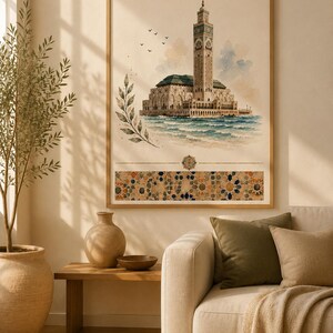 May include: A framed wall art print featuring a watercolor illustration of the Hassan II Mosque in Casablanca, Morocco, with a tall minaret, blue ocean waves, a leafy branch, and a decorative geometric tile pattern border at the bottom.