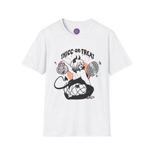 May include: A white short-sleeve t-shirt featuring a graphic illustration of a horned character with a tail, wearing fishnet stockings, holding a jack-o'-lantern and a lollipop. The text "THICC OR TREAT" is printed in black above the character.