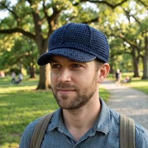 May include: A dark navy blue baseball cap constructed from crocheted yarn. The cap features a structured crown with a visible stitch pattern and a firm, curved brim. The design is simple and functional, showcasing the texture of the yarn work.