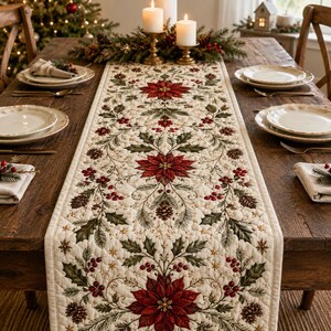 May include: A cream-colored quilted table runner featuring a repeating pattern of red poinsettia flowers, green holly leaves, pine cones, and red berries. The runner is centered on a dark wooden dining table set with white plates and napkins.