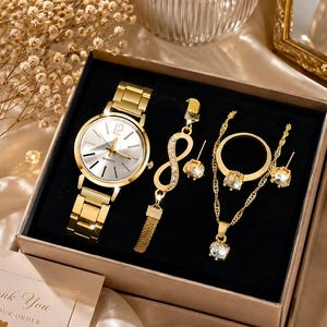 Peut inclure: Un ensemble de bijoux doré dans une boîte comprenant une montre à quartz avec un cadran métallique, un bracelet symbole infini avec des pierres claires, une paire de boucles d'oreilles, une bague avec une pierre claire et un collier pendentif.