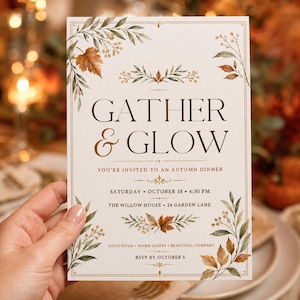 May include: A rectangular invitation card with a cream background featuring watercolor autumn leaves and berries in the corners. The text reads GATHER & GLOW, YOU'RE INVITED TO AN AUTUMN DINNER, SATURDAY OCTOBER 18 6:30 PM, THE WILLOW HOUSE 24 GARDEN LANE, GOOD FOOD WARM LIGHTS BEAUTIFUL COMPANY, RSVP BY OCTOBER 5.