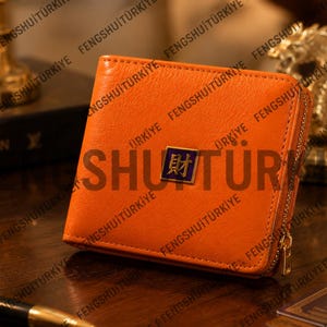 May include: A square orange leather wallet with a gold-tone zipper closure along the side. Centered on the front is a small square emblem featuring a dark blue background with a gold Chinese character for wealth, enclosed in a thin gold border.