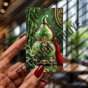May include: A green gourd-shaped ornament featuring gold-colored decorative patterns and Chinese characters. The ornament is accented with a red cord and a red tassel, and it rests on a circular, ornate gold-colored base with intricate detailing.
