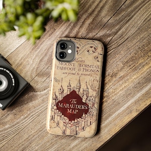 May include: A beige smartphone case featuring a detailed illustration of a castle and the text "Messrs. Moony, Wormtail, Padfoot & Prongs are proud to present The Marauder's Map" in a vintage parchment style with dark brown ink and a deep red center.