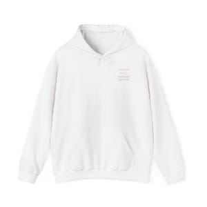 Peut inclure: Un sweat-shirt à capuche blanc à manches longues avec une poche kangourou sur le devant et un cordon de serrage. La poitrine porte l'inscription MAISON MOO MAMAN QUI OSE imprimée en rose clair dans une police simple et sans empattement.