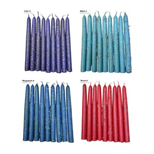 Pode incluir: Quatro conjuntos de oito velas cónicas dispostas em filas, rotuladas como Lilac, Mint, Mugwort e Rose. Cada vela apresenta uma superfície texturizada com pedaços botânicos secos incrustados. As cores são roxo, azul claro, azul escuro e vermelho.