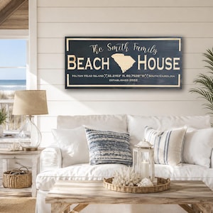 May include: A rectangular dark blue wooden sign with a light wood border and lettering that reads The Smith Family BEACH HOUSE, featuring a map of South Carolina, coordinates for Hilton Head Island, and the text ESTABLISHED 2022.