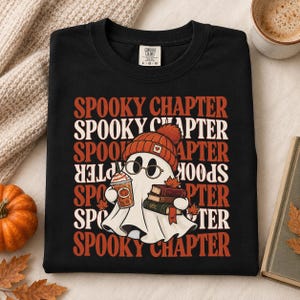Può includere: Una t-shirt nera con la grafica di un fantasma bianco che indossa un berretto arancione e occhiali rotondi. Il fantasma tiene in mano una tazza di caffè e una pila di libri. Il testo "SPOOKY CHAPTER" è ripetuto in arancione e bianco sullo sfondo.