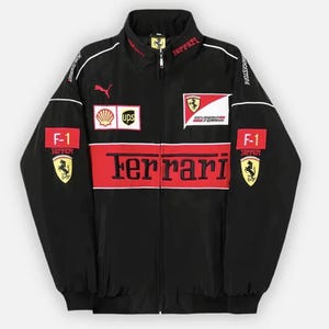 Pode incluir: Um casaco preto com fecho de correr, apresentando uma faixa horizontal vermelha no peito com a palavra Ferrari em texto preto. O casaco inclui vários logótipos de patrocinadores, o emblema Scuderia Ferrari, emblemas F-1 e um logótipo Puma.