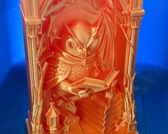 May include: A bright orange 3D printed book nook insert featuring a detailed owl perched within an arched gothic structure. The owl is depicted reading an open book, with a stack of books nearby and a small lantern at its feet, all framed by tree branches.
