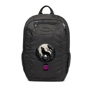 May include: A black backpack featuring a circular graphic of a wolf howling at a full moon with a raven perched on a tree branch. Below the graphic is a small rectangular icon with a pink and blue pattern. The bag has a top handle and side pockets.