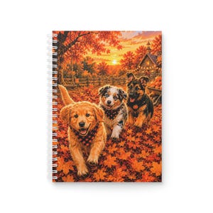 Può includere: Un taccuino a spirale con l'illustrazione di tre cuccioli che corrono tra foglie autunnali arancioni e rosse. I cuccioli, un golden retriever, un cane maculato e un pastore tedesco, indossano tutti piccole bandane a fantasia.