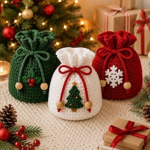 May include: Three crochet drawstring gift bags in green, white, and red. The green bag features a holly berry applique, the white bag has a Christmas tree, and the red bag displays a white snowflake. Each bag includes a drawstring with wooden beads.