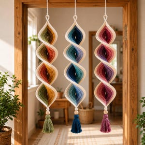 Può includere: Tre decorazioni a spirale sospese realizzate in filato all'uncinetto. Ogni pezzo presenta una sfumatura di colore: una in verde e arancione, una in blu e turchese e una in rosa e viola. Ogni spirale termina con una perlina di legno e una nappa.