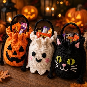 May include: Three crocheted drawstring bags featuring Halloween designs: an orange pumpkin with a black face, a white ghost with black eyes and pink cheeks, and a black cat with green eyes and pink ears. Each bag is filled with assorted candy.