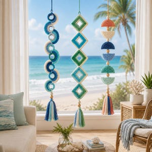 May include: Three vertical hanging wall decorations featuring crocheted elements in shades of blue, green, and coral. The left piece has circular shapes, the center has diamond shapes, and the right has semi-circles, all finished with tassels.
