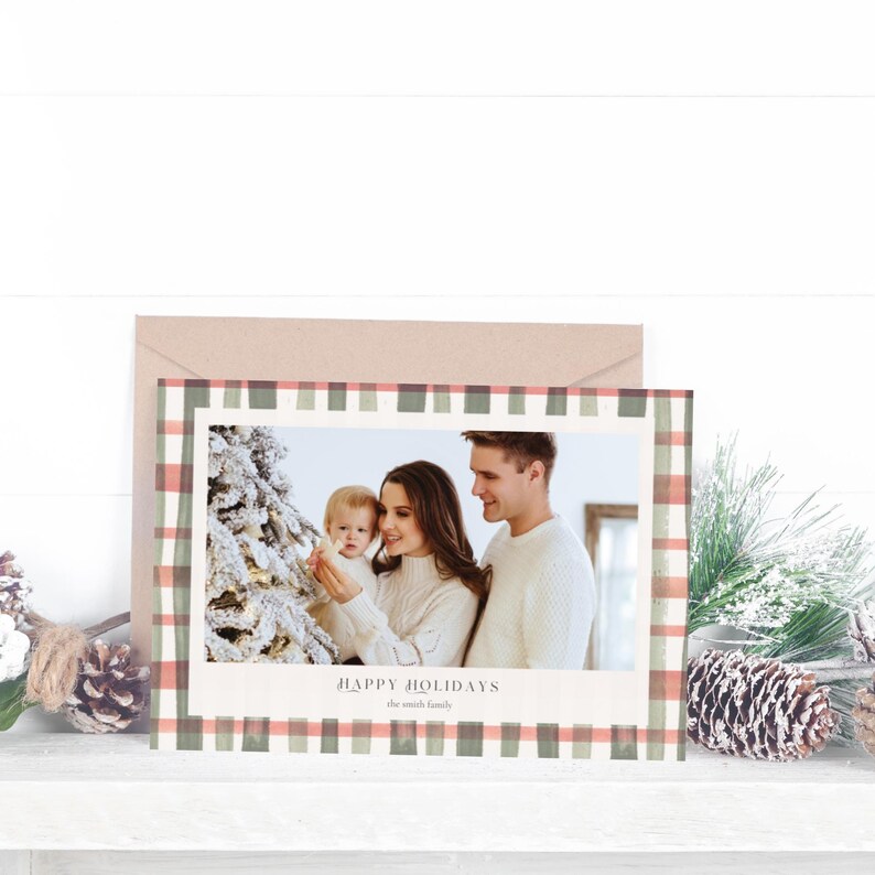 May include: A Christmas greeting card with a family photo framed by a green and coral plaid border. The card says "Happy Holidays" and includes the family name. An envelope is visible behind the card.