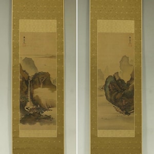 May include: Two vertical Asian scroll paintings. Each depicts a landscape scene with mountains, waterfalls, and trees in muted tones. The borders are a patterned gold colour, and the overall aesthetic is traditional.
