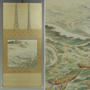 May include: A traditional Japanese scroll painting depicting a coastal scene with boats on the water. The artwork features a mountain range in the background, with a gold patterned border and cream-colored fabric.