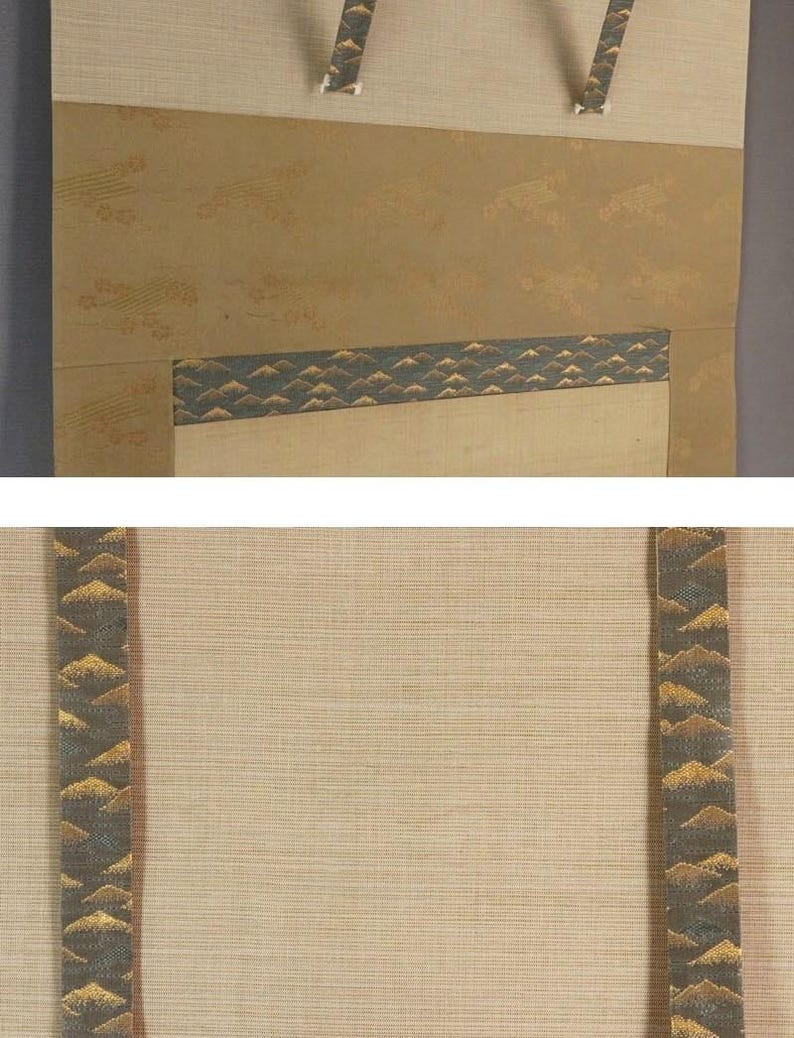 May include: A traditional Japanese scroll painting with a beige background and decorative bands. The bands feature a repeating pattern of gold and dark green mountain-like shapes. The scroll has a textured appearance and is designed to be hung.