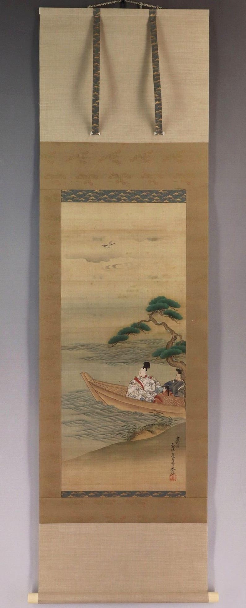 May include: Japanese scroll painting depicting two figures in a boat near a tree, with a serene landscape background. The artwork features muted colors, a traditional style, and is mounted on a neutral-toned fabric.