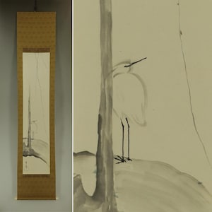 Peut inclure: Peinture sur rouleau de style japonais avec une illustration minimaliste à l'encre d'un héron blanc. L'œuvre représente l'oiseau près d'un arbre, avec un paysage simple en arrière-plan. Le rouleau a une bordure marron et un dessus décoratif.
