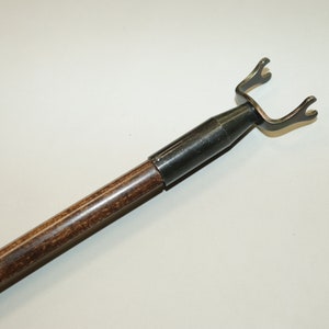 May include: A wooden and metal tool with a hook on the end. The hook is designed to help remove items from hard to reach places.