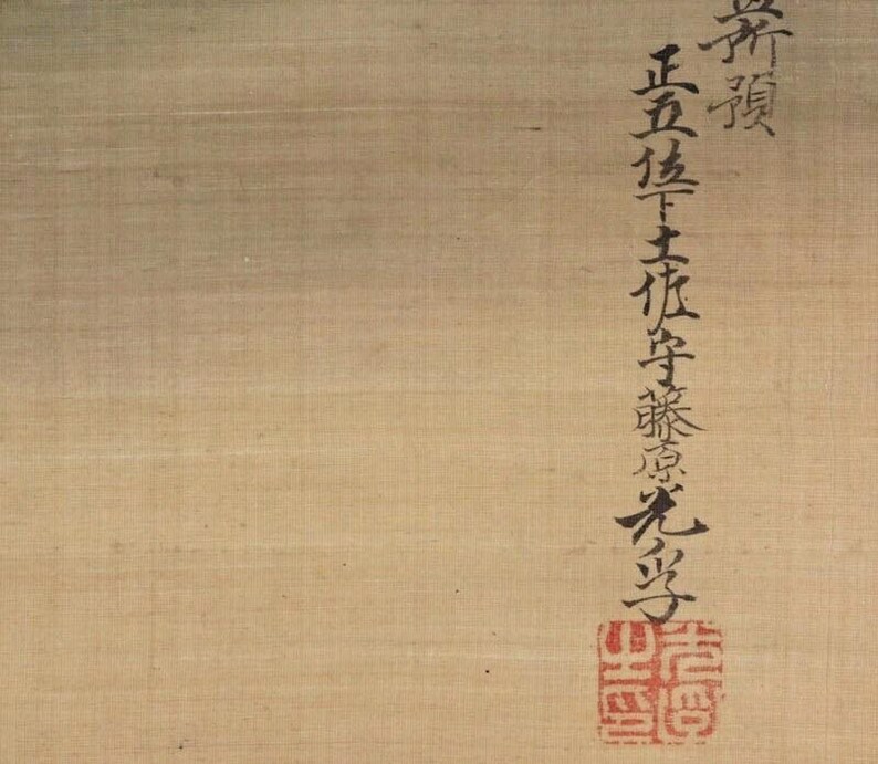 May include: Close-up of a beige-colored scroll with black calligraphy and a red seal. The calligraphy is vertical and includes Japanese characters. The seal is square and features intricate red markings.