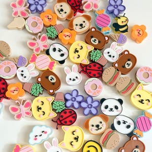 May include: A collection of small, colourful resin cabochons featuring various shapes including smiling clouds, butterflies, ladybugs, pandas, bears, rabbits, cats, flowers, doughnuts, hamburgers, sweets, and ice cream cones in a variety of bright colours.