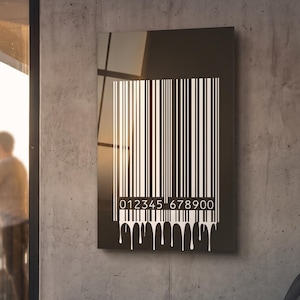 Peut inclure: Une décoration murale rectangulaire présentant un fond noir avec un grand code-barres blanc. Le code-barres inclut la séquence numérique 012345 678900 à la base, avec des coulures de peinture blanche s'étendant vers le bas du motif.